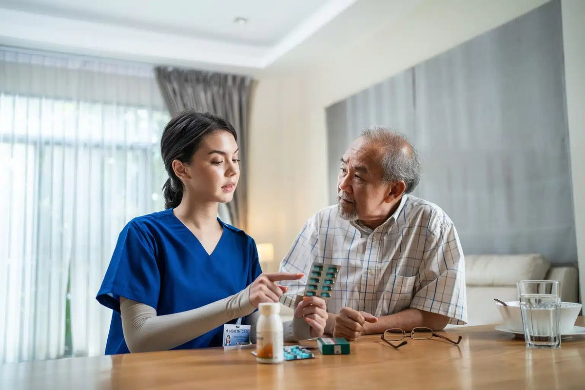 A registered nurse in Adelaide helping an older patient with medication