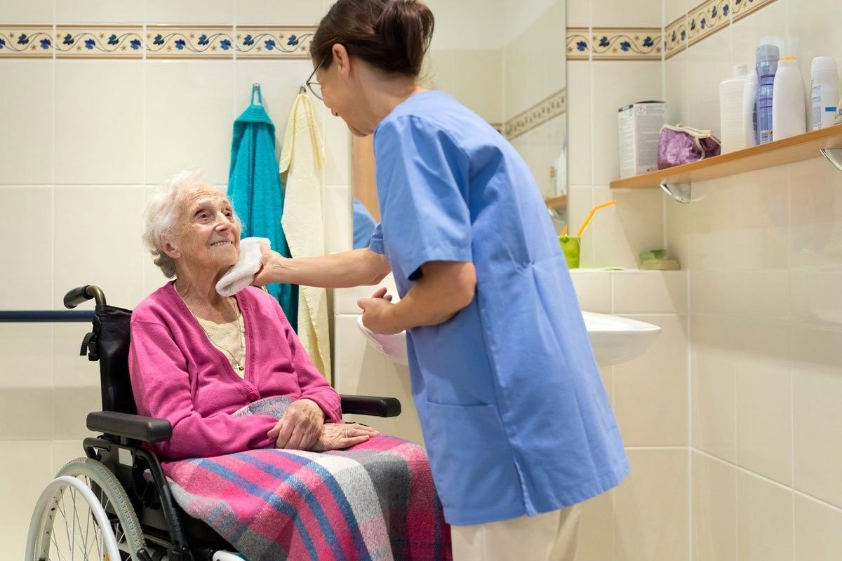 A nurse in Adelaide helping an elderly woman in a wheelchair with personal care